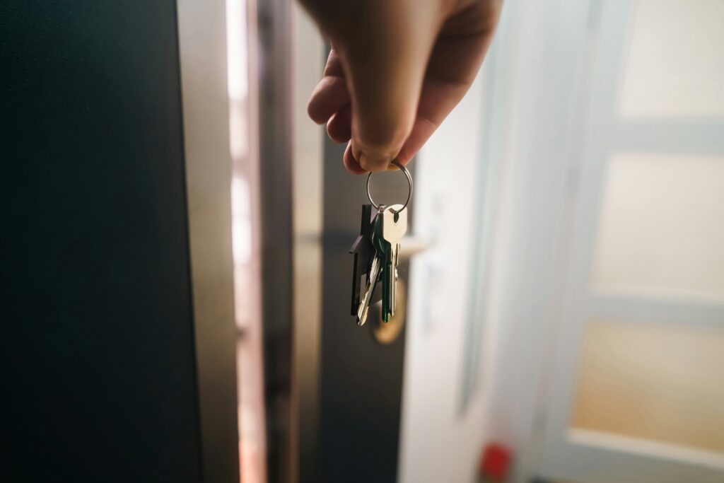 Hand holding up house keys. Photo by Jakub Żerdzicki on Unsplash