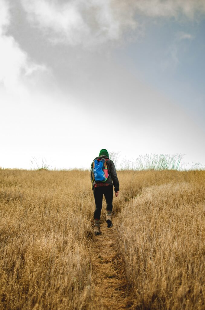 Woman rucking up a grassy hill—photo by Jared Murray on Unsplash.