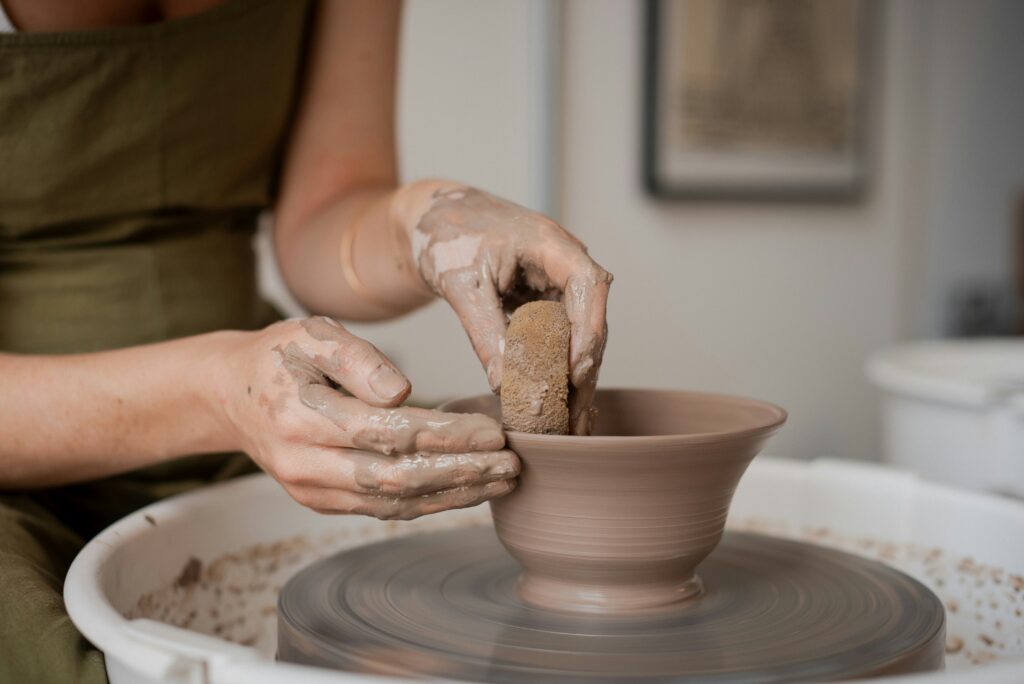 Millennial woman making bowl at a pottery wheel.